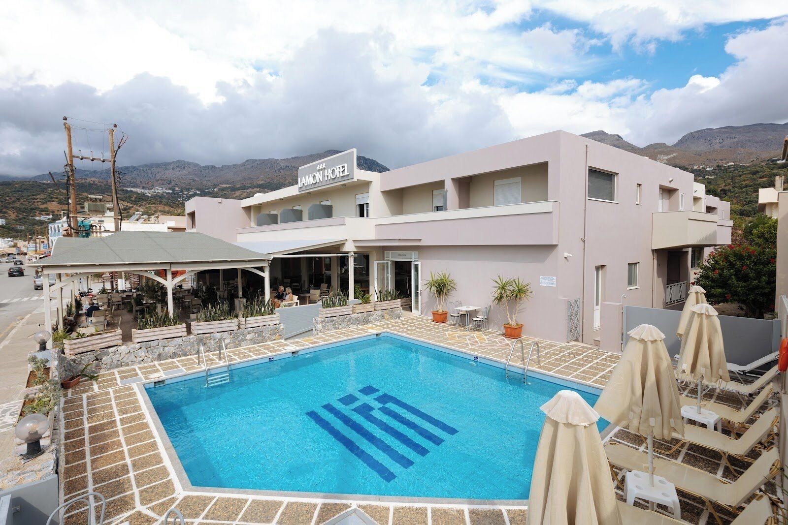 A hotel with a swimming pool, outdoor seating, and a view of mountains.