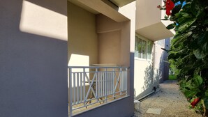 Ein Gebäude mit geschlossenem Eingangstor, einem Kiesweg und einem kleinen Gartenbereich mit roten Blumen.