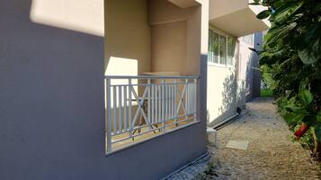 A building with a gated entrance, a gravel pathway, and a small garden area with red flowers.