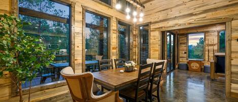 Un interior de madera con una mesa de comedor, sillas y ventanas grandes.
