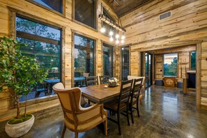 Un intérieur en bois avec une table à manger, des chaises et de grandes fenêtres.