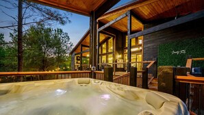 Een hottubgedeelte met een houten terras, grote ramen en een trap naar een hoger gelegen niveau.