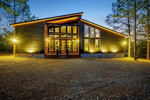 Une cabane en bois avec une allée en gravier, de grandes fenêtres et des fondations en pierre.