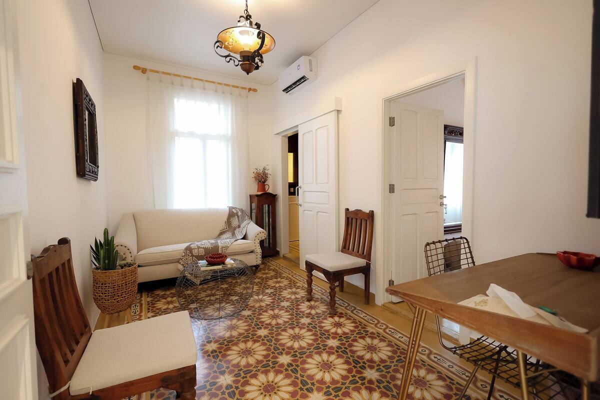 Una sala de estar con un sofá, una mesa de comedor y un suelo con diseño.