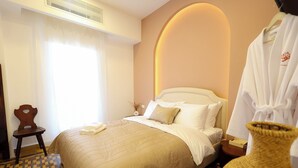 A hotel room with a bed, a chair, a round table, and a robe. - Dar Khawla (Beirut)
