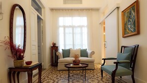 A living room with a patterned floor, a sofa, a chair, a coffee table, a mirror, and a painting. - Dar Khawla (Beirut)