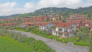 A residential area with terraced houses, a main road, and a hill in the background. - Villetta Bucaneve - Locz (Padenghe sul Garda)