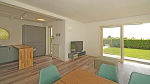 A modern kitchen with a built-in fridge, a wooden table, and a TV on a stand. - Villetta Bucaneve - Locz (Padenghe sul Garda)