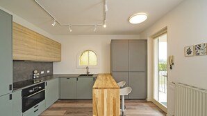A modern kitchen with a central island, built-in appliances, and a large window. - Villetta Bucaneve - Locz (Padenghe sul Garda)