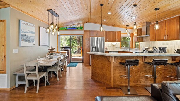 Eine moderne Küche mit Holzausstattung, einem Edelstahlkühlschrank und einer Bar mit Barhocker.