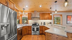 Eine moderne Küche mit Holzschränken, Edelstahlgeräten und Pendelleuchten.