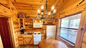 A wooden cabin kitchen with a stove, sink, refrigerator, and a dining table. - Best Catch #49 Cabin in town, walking distance to the courthouse square. (Mountain View)
