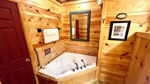 A wooden cabin bathroom with a wooden door, a bathtub, a mirror, and a towel rack. - Best Catch #49 Cabin in town, walking distance to the courthouse square. (Mountain View)