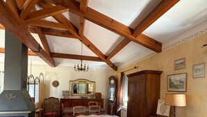 A room with a wooden ceiling, a sofa, a round table, a fireplace, and a mirror. - Maison en Bord de mer - Casa L'albitronu (Pietrosella)