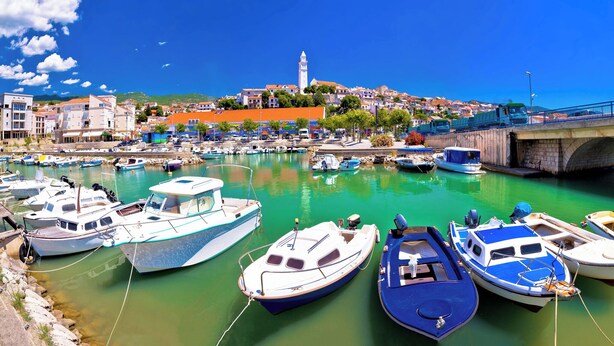 A harbor with boats docked, a bridge, and buildings in the background. - Studio with air conditioning, garden and terrace (Novi Vinodolski)