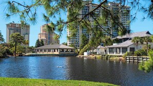 Vista del lago con un muelle, un pabellón y edificios residenciales.