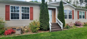 A single-story house with a front porch, a stone foundation, and a small garden with various plants. - 
Mountain Retreat in Blue Ridge Mountains. Privacy!  Owner Managed. (Fleetwood)