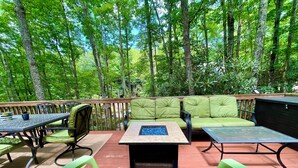 Une terrasse extérieure avec un canapé vert, deux tables et des chaises vertes.