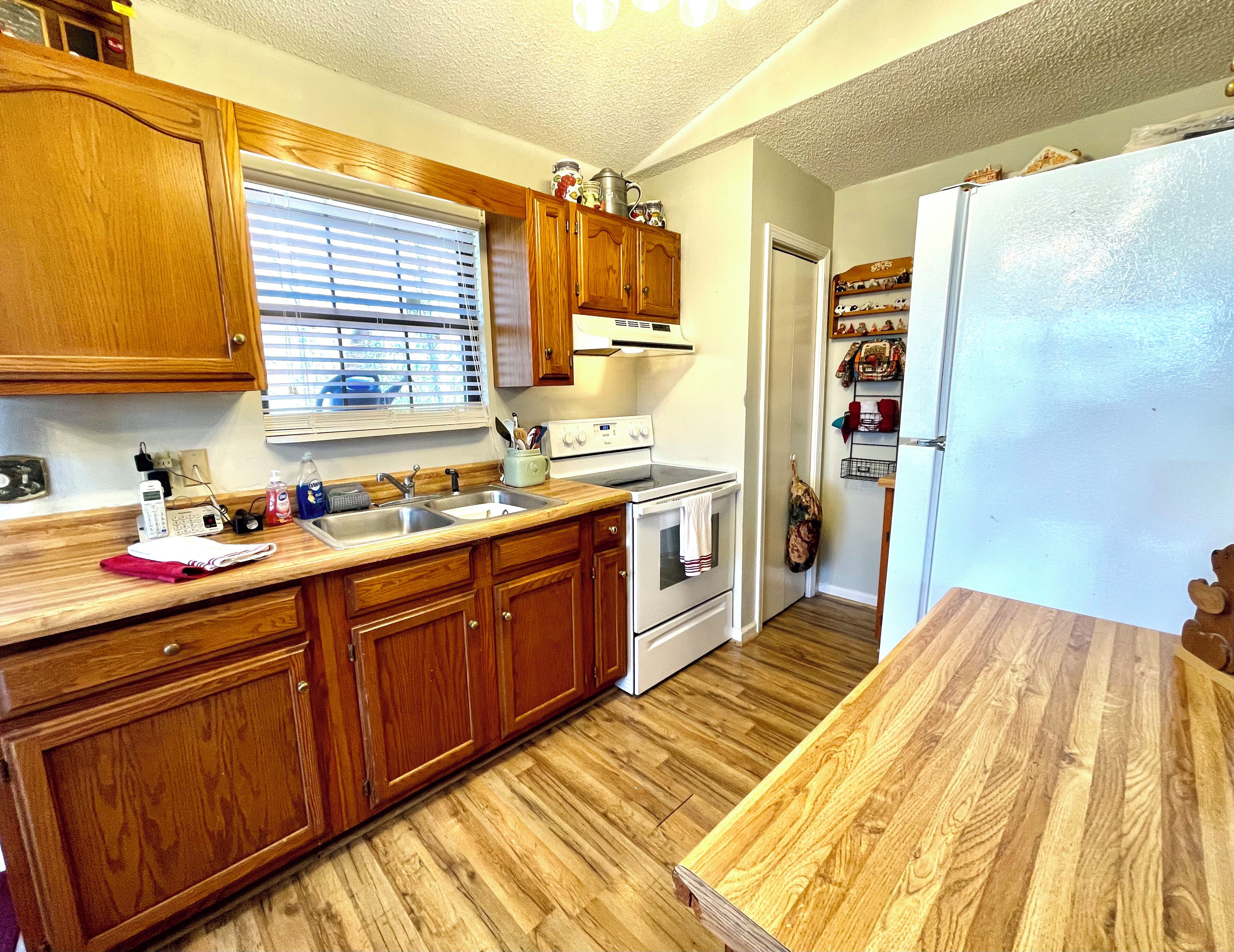 Une cuisine avec des meubles de rangement en bois, une cuisinière, un évier et un réfrigérateur.