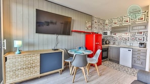 Une cuisine de taille réduite équipée d’un téléviseur, d’une table à manger et de chaises.