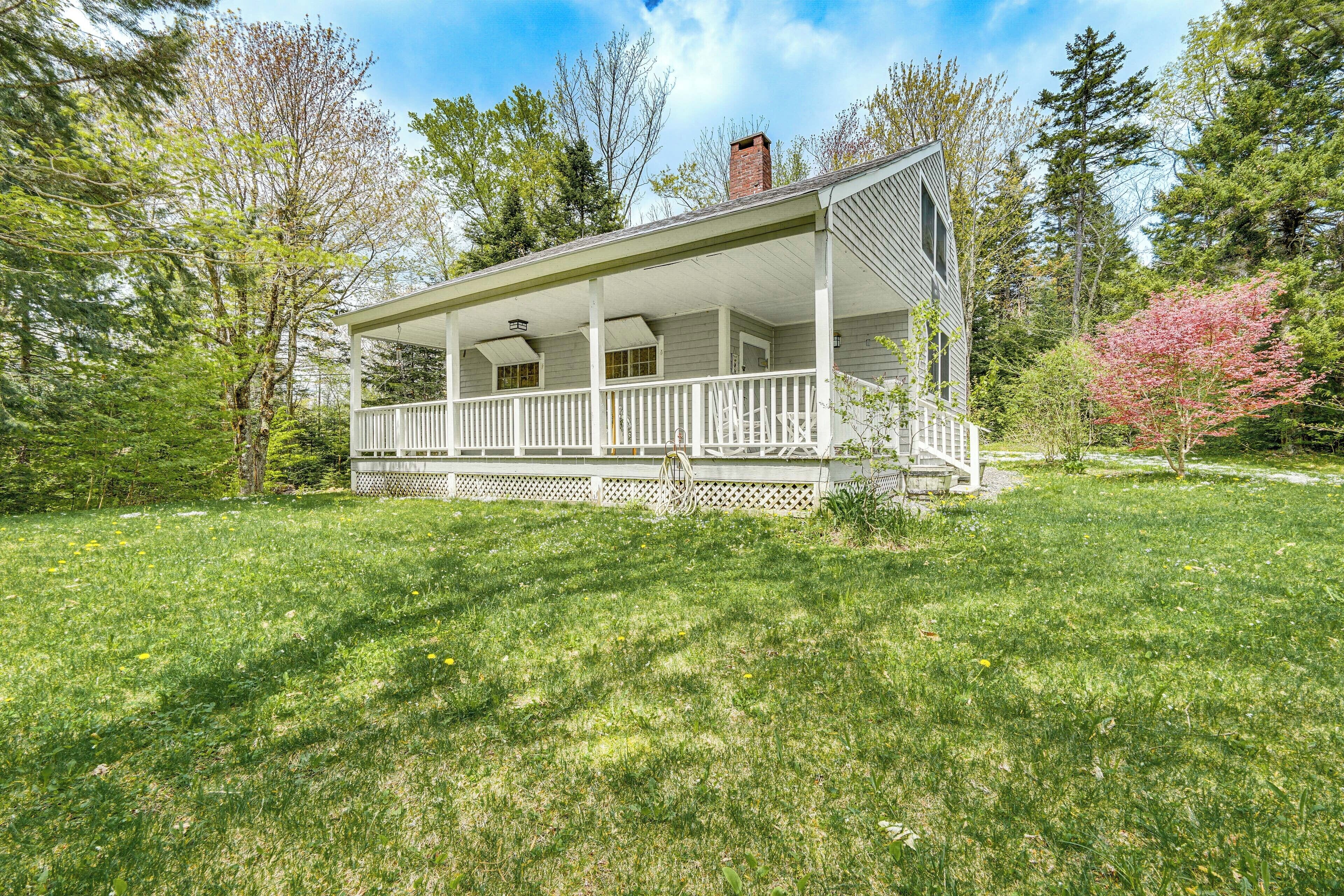 A two-story house with a covered porch, surrounded by a well-maintained lawn and trees.
