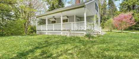 A two-story house with a covered porch, surrounded by a well-maintained lawn and trees.