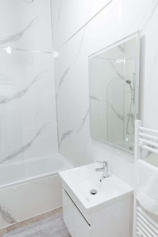 A modern bathroom with a bathtub, a sink, and a glass shower enclosure.