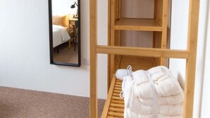 A room with a wooden wardrobe, a mirror, and a bed.