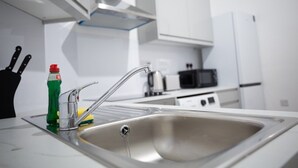 A modern kitchen with a stainless steel sink, a faucet, and a bottle of dish soap. - Cozy corner in London (London)