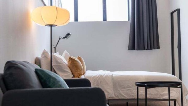 A modern bedroom with a bed, a desk, a lamp, and a window with curtains. - Cozy corner in London (London)
