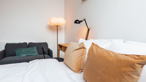 Ein Hotelzimmer mit einem Bett, einer Couch, einem Nachttisch und zwei Lampen.