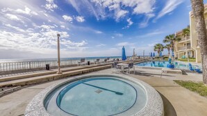 A pool area with a view of the ocean, a palm tree, and a building with balconies. - ☀️Gulf Front Condo with Great Views-Latitude 29 #36☀️ (Panama City Beach)