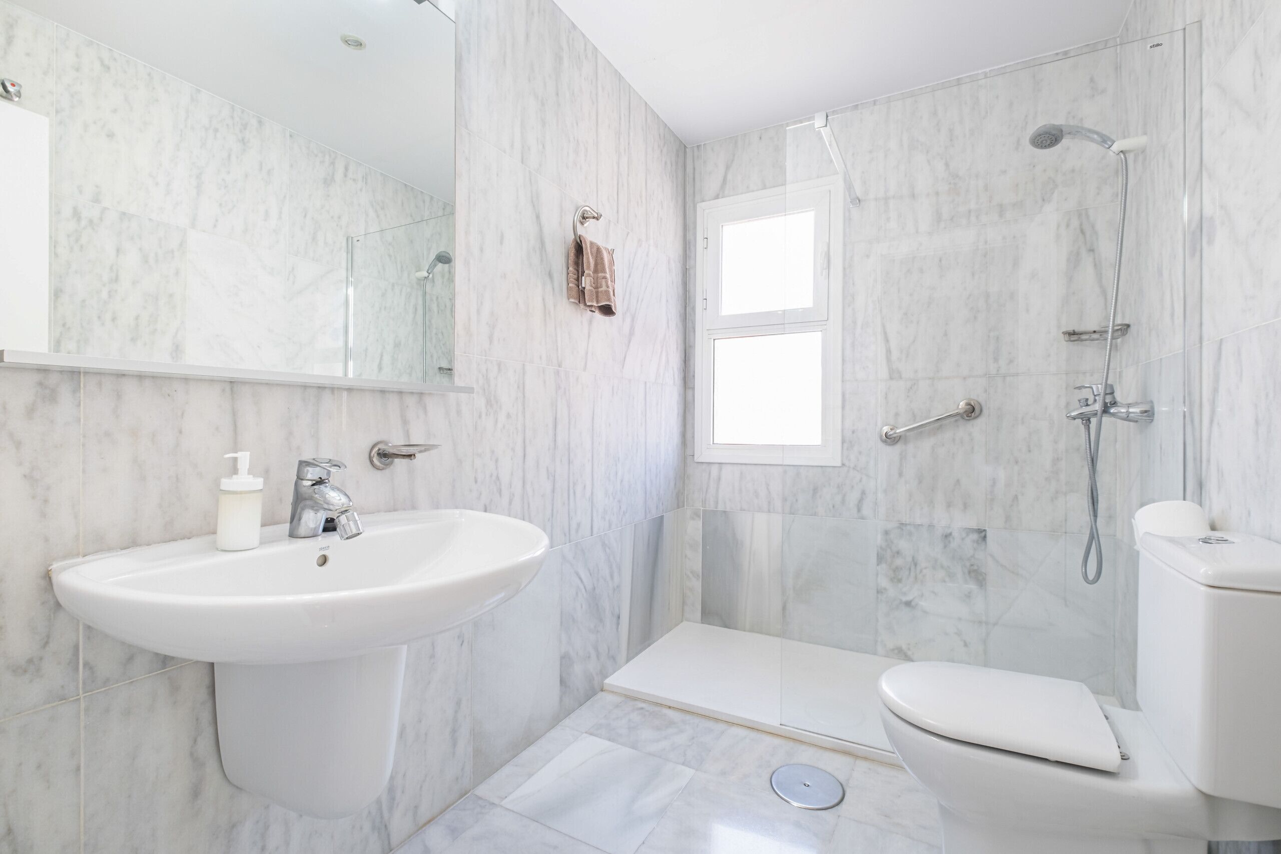 Un baño moderno con lavamanos, inodoro y ducha.