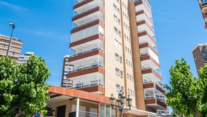 A multi-story residential building with balconies, a central entrance with a canopy, and a street lamp.