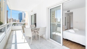 A modern apartment with a balcony, a dining area, and a bedroom.