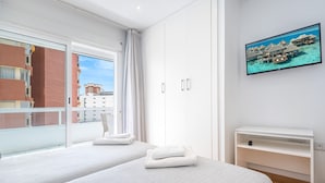 Una habitación de hotel moderna con dos camas, un televisor y un balcón con vista a la ciudad.