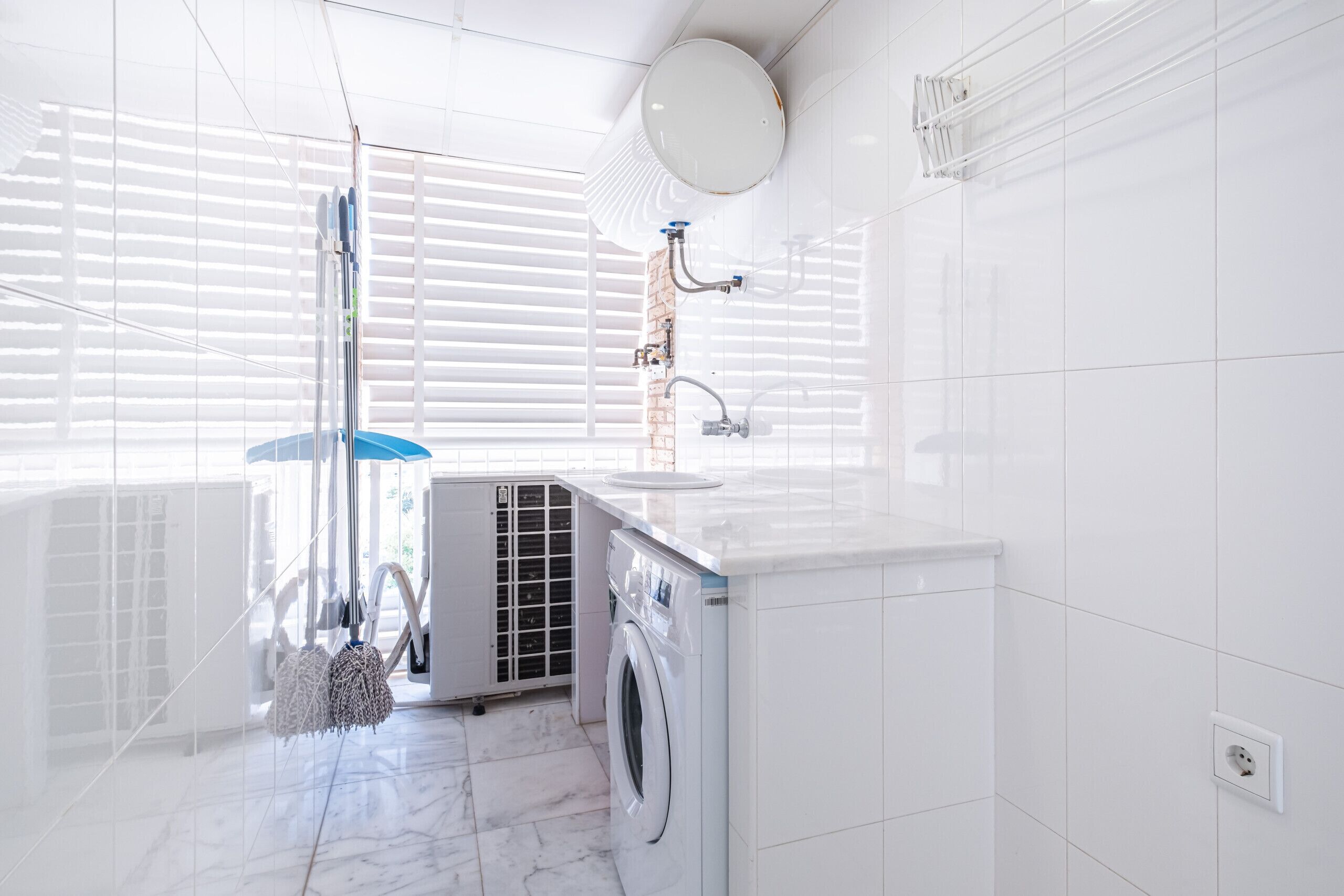 Ein modernes Badezimmer mit Waschmaschine, Waschbecken und einem großen Spiegel.