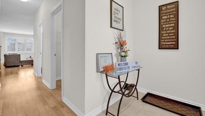 A hallway with a welcome sign, motivational posters, and a small table with a vase of flowers. - Cozy home minutes from Niagara Falls (Thorold)