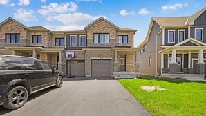 A multi-story residential building with a driveway, a car, and a basketball hoop. - Cozy home minutes from Niagara Falls (Thorold)