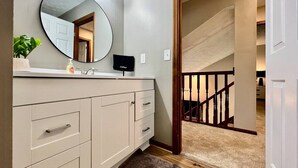 A bathroom with a vanity, mirror, and a plant.
