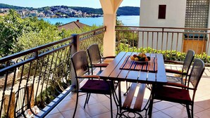 A terrace with a table and chairs, a view of a lake, and a distant town.
