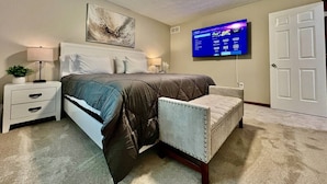A bedroom with a bed, a TV, a chair, a nightstand, and a door. - Newly Remodeled home in Liberty (Liberty Township)