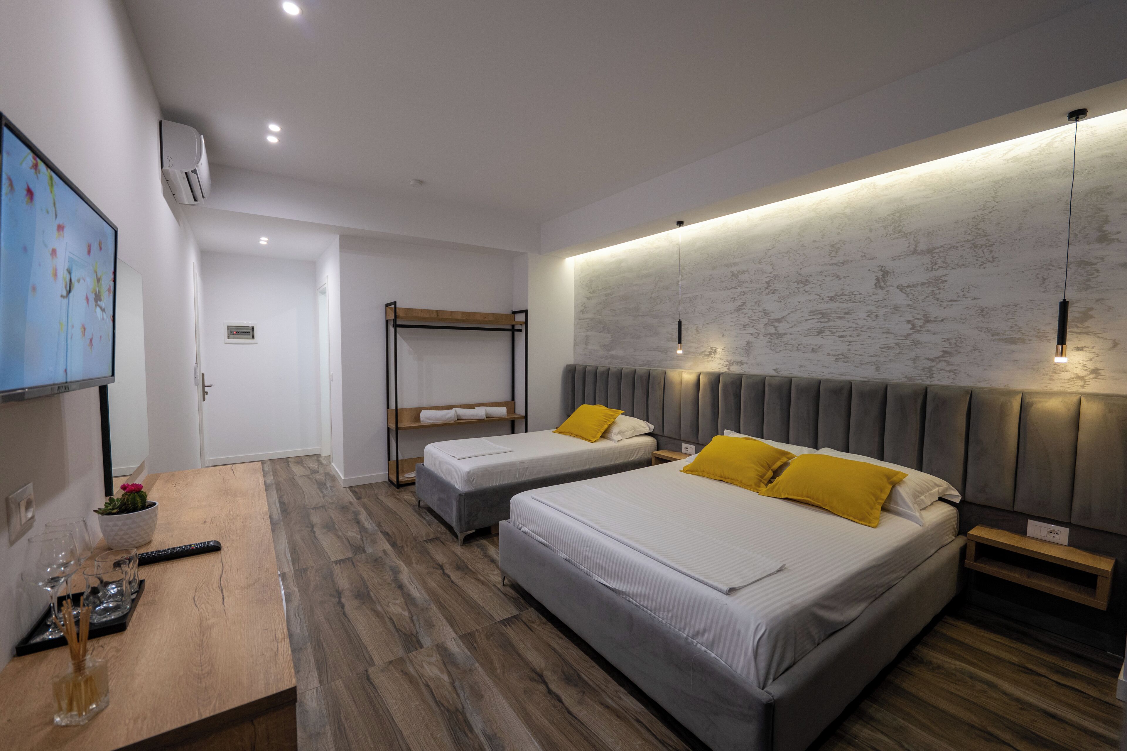 A modern hotel room with two beds, a wooden table, and a TV.
