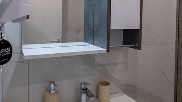 A bathroom with a white sink, a mirror, and a towel dispenser.