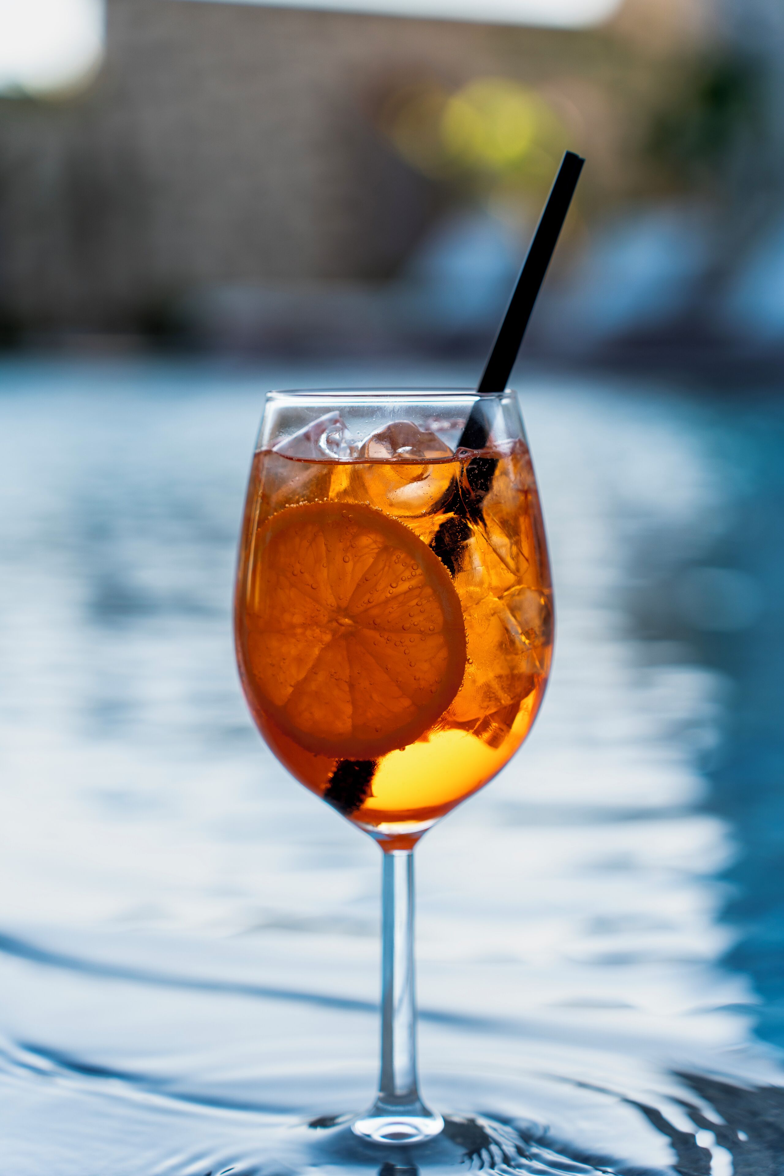 A glass of iced tea with a lemon slice and a straw, placed on a reflective surface.