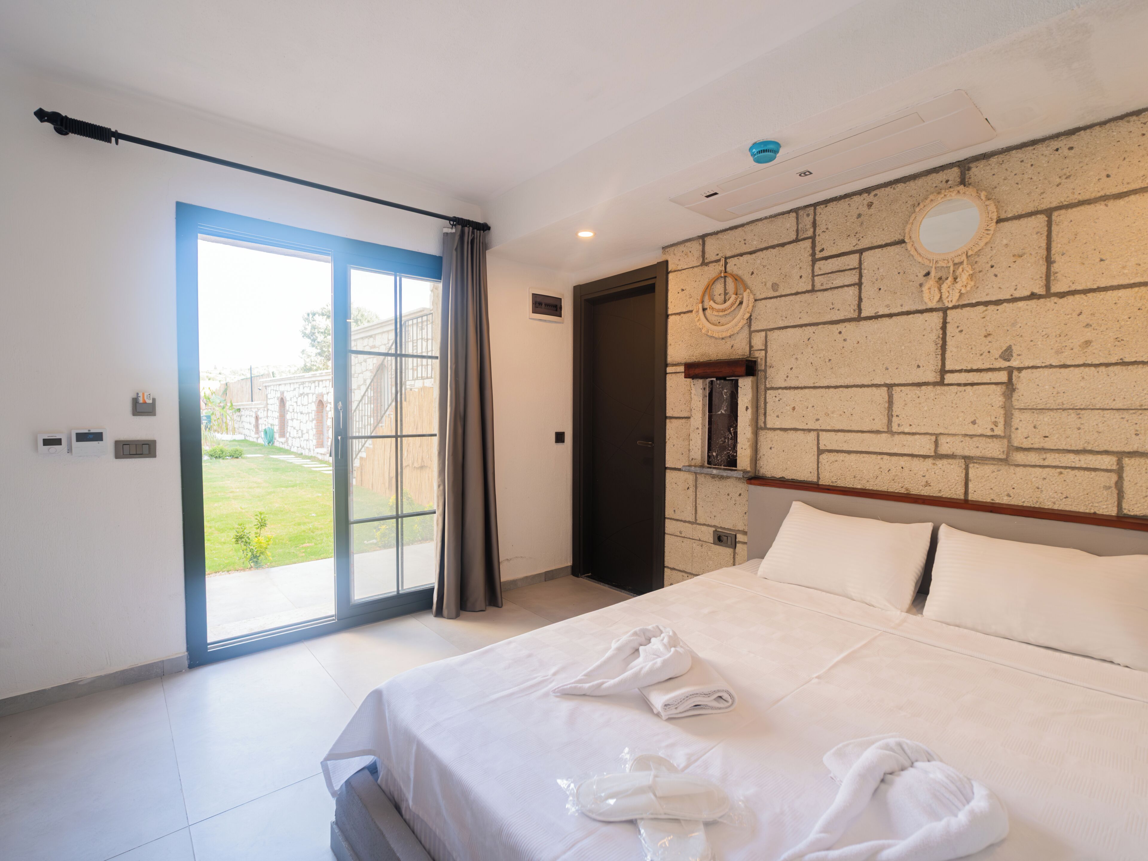 A bedroom with a bed, a bathroom, and a view of a garden.