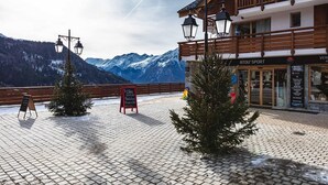 Eine Berglodge mit Holzfassade, einem Schild und Blick auf schneebedeckte Berge.