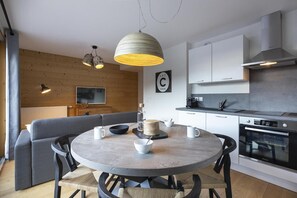 A modern kitchen with white cabinets, a built-in oven, and a dining area with a round table and chairs. - Wifi, 100m from resort center, balcony, parking, tv, ski locker, 40-52m², Vaujany (Vaujany)