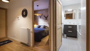 Ein Schlafzimmer mit Bett, Heizkörper und einer Tür zu einem Badezimmer mit Spiegel und Waschbecken.