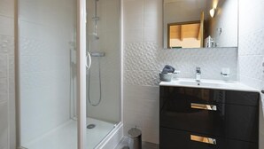 A modern bathroom with a glass-enclosed shower, a vanity with a mirror, and a tiled backsplash. - Wifi, 100m from resort center, balcony, parking, tv, ski locker, 55m², Vaujany (Vaujany)